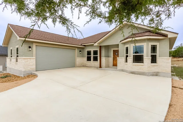 a view of a white house with a large tree