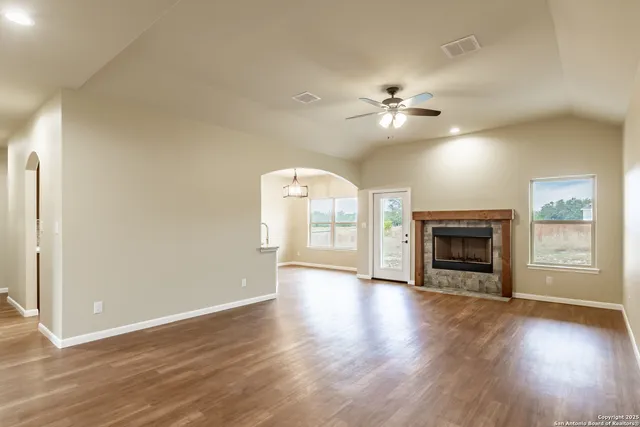 an empty room with wooden floor fireplace and windows