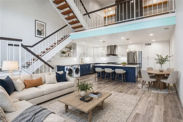 a kitchen with a stove a refrigerator a sink and a dining table with wooden floor