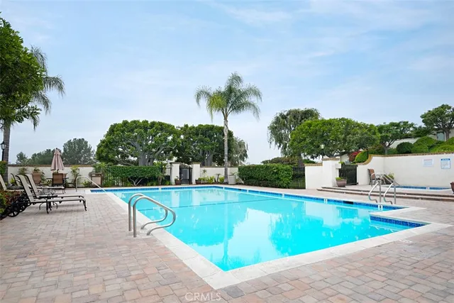 a view of a swimming pool with a lounge chair and palm trees