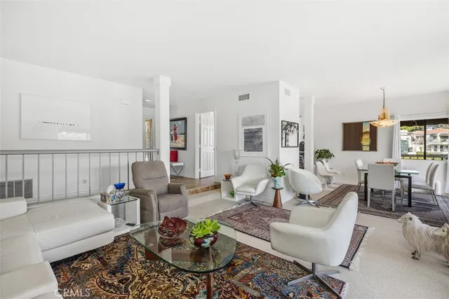 a living room with furniture potted plant and open kitchen view