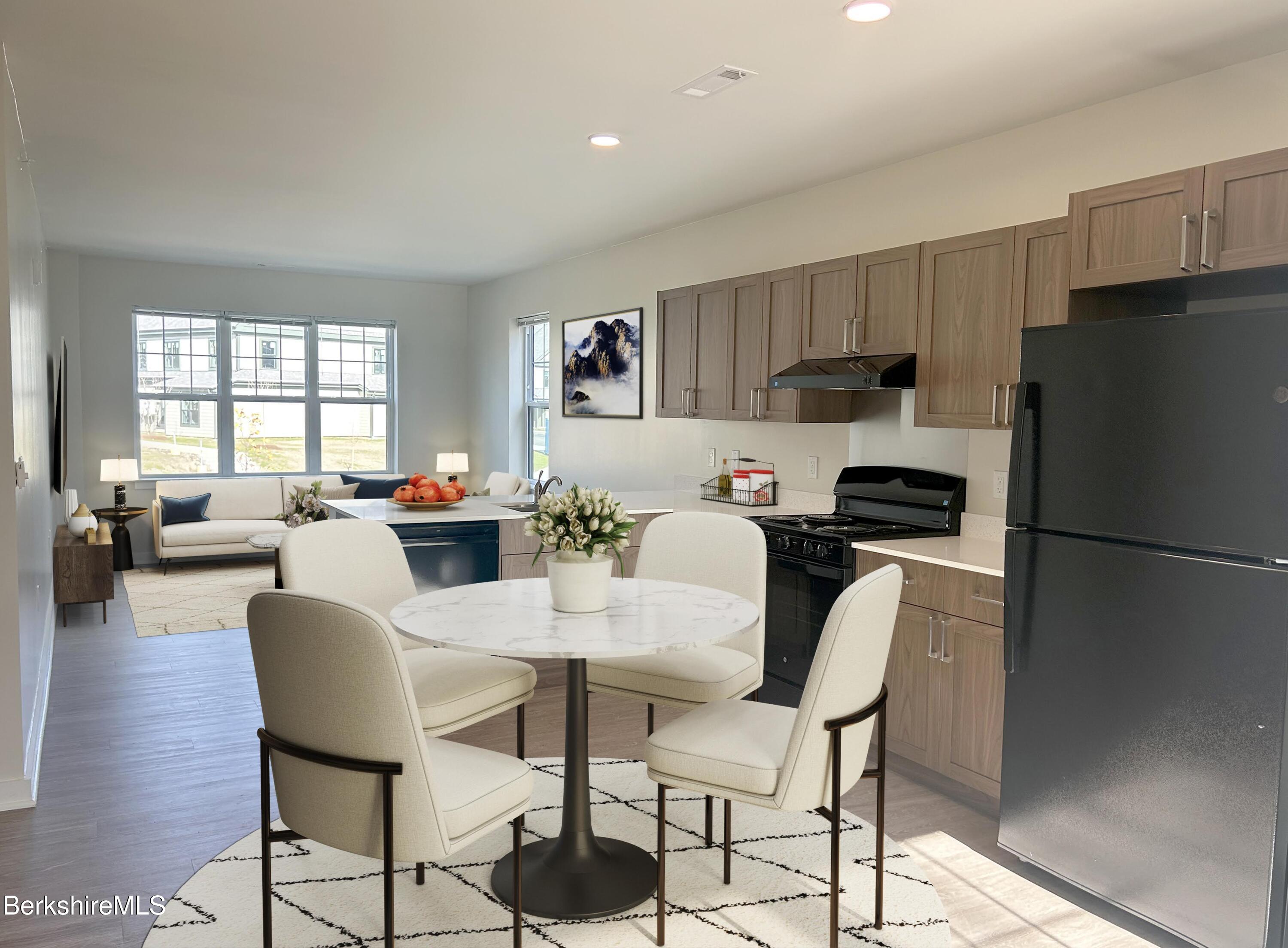 9 Brushwood Way, Unit 9 Lenox, MA 01240 - Photo 4 of 15 a kitchen with stainless steel appliances a refrigerator a stove a dining table and chairs with wooden floor