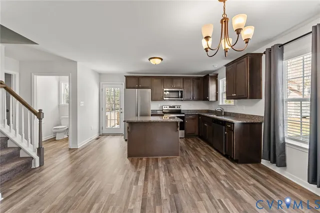 a kitchen with stainless steel appliances granite countertop a refrigerator a stove top oven a sink dishwasher and wooden cabinets