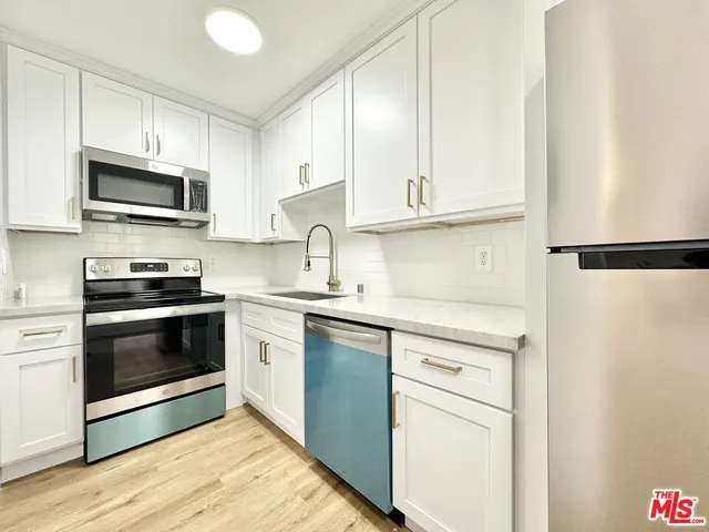 a kitchen with granite countertop white cabinets and stainless steel appliances