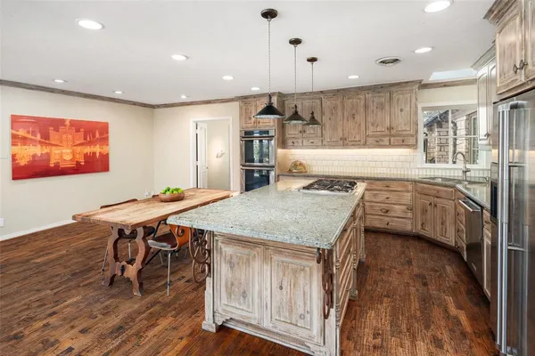 a dining hall with stainless steel appliances granite countertop a kitchen island a stove and a wooden floors