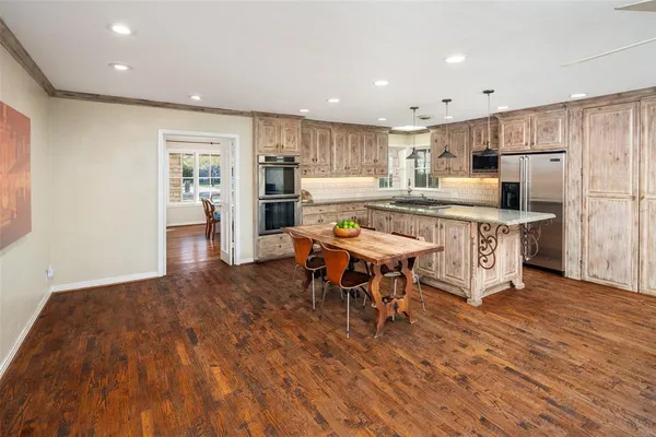 a open kitchen with stainless steel appliances granite countertop a dining table chairs refrigerator and sink