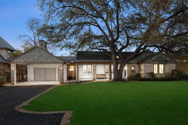 a front view of a house with a garden and trees