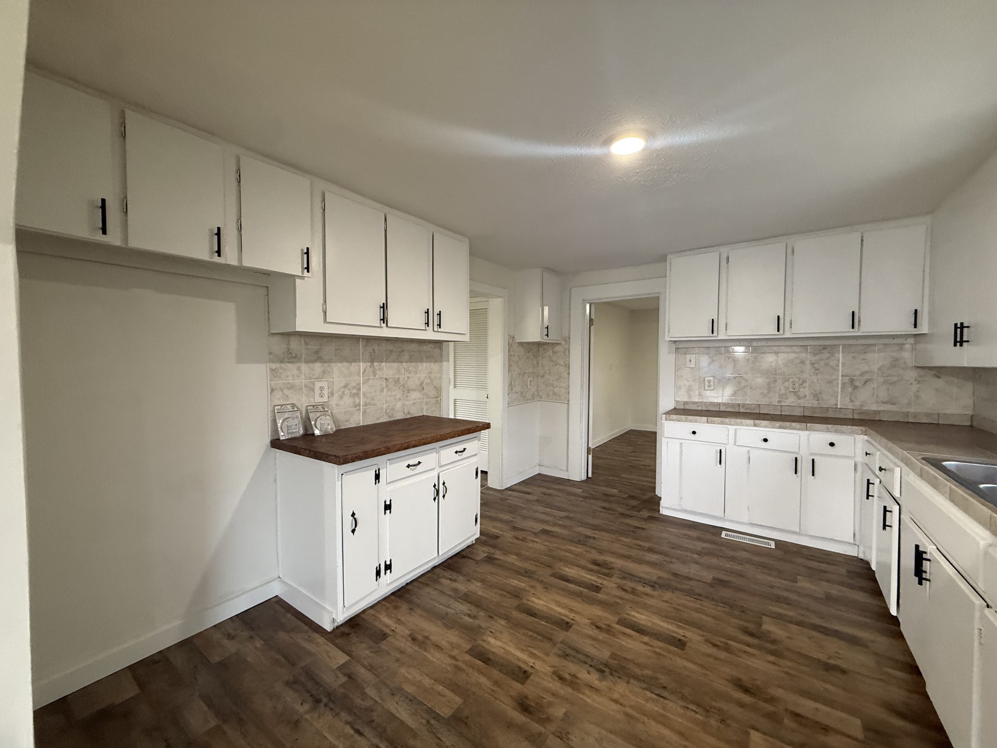 209 West 3rd Avenue Hohenwald, TN 38462 - Photo 7 of 12 a kitchen with granite countertop a stove top oven a sink and white cabinets
