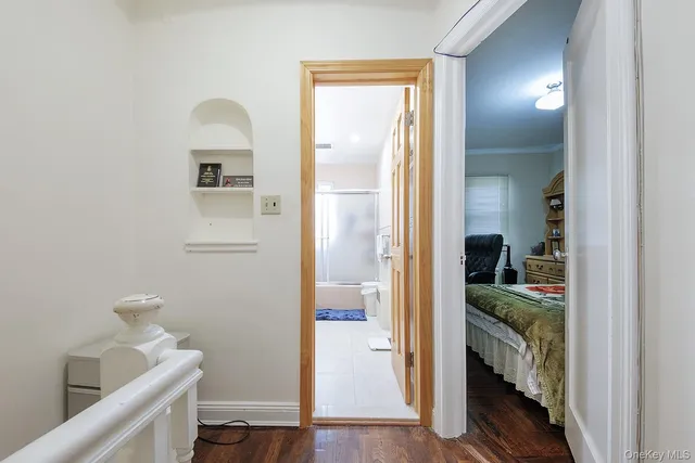 a view of a hallway with bathroom and wooden floor