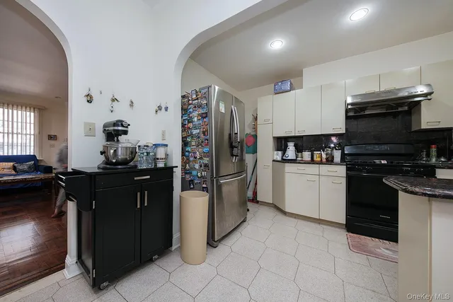 a kitchen with granite countertop a refrigerator and a stove top oven