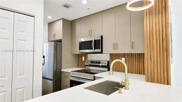 a kitchen with stainless steel appliances a sink a stove a refrigerator and cabinets