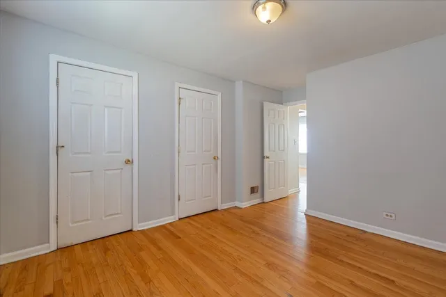 a view of an empty room with wooden floor and windows