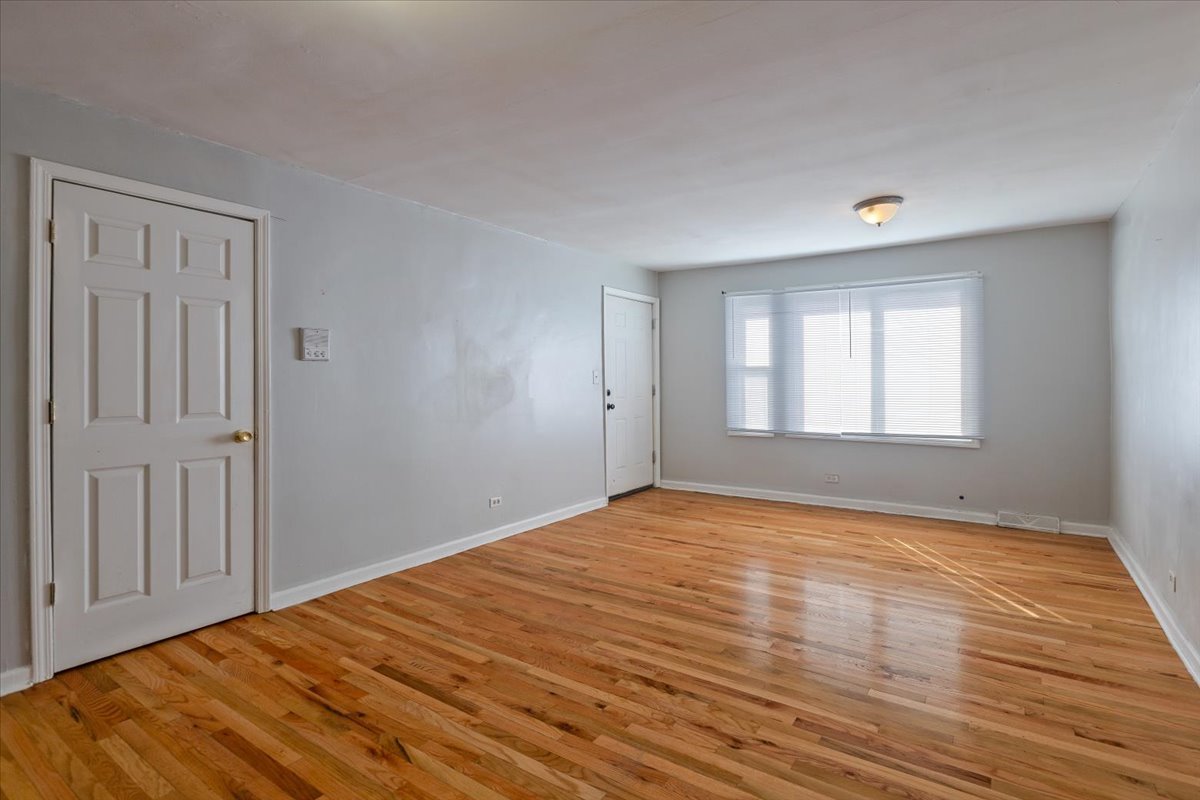 128 North Menard Avenue Chicago, IL 60644 - Photo 5 of 20 a view of an empty room with wooden floor and a window