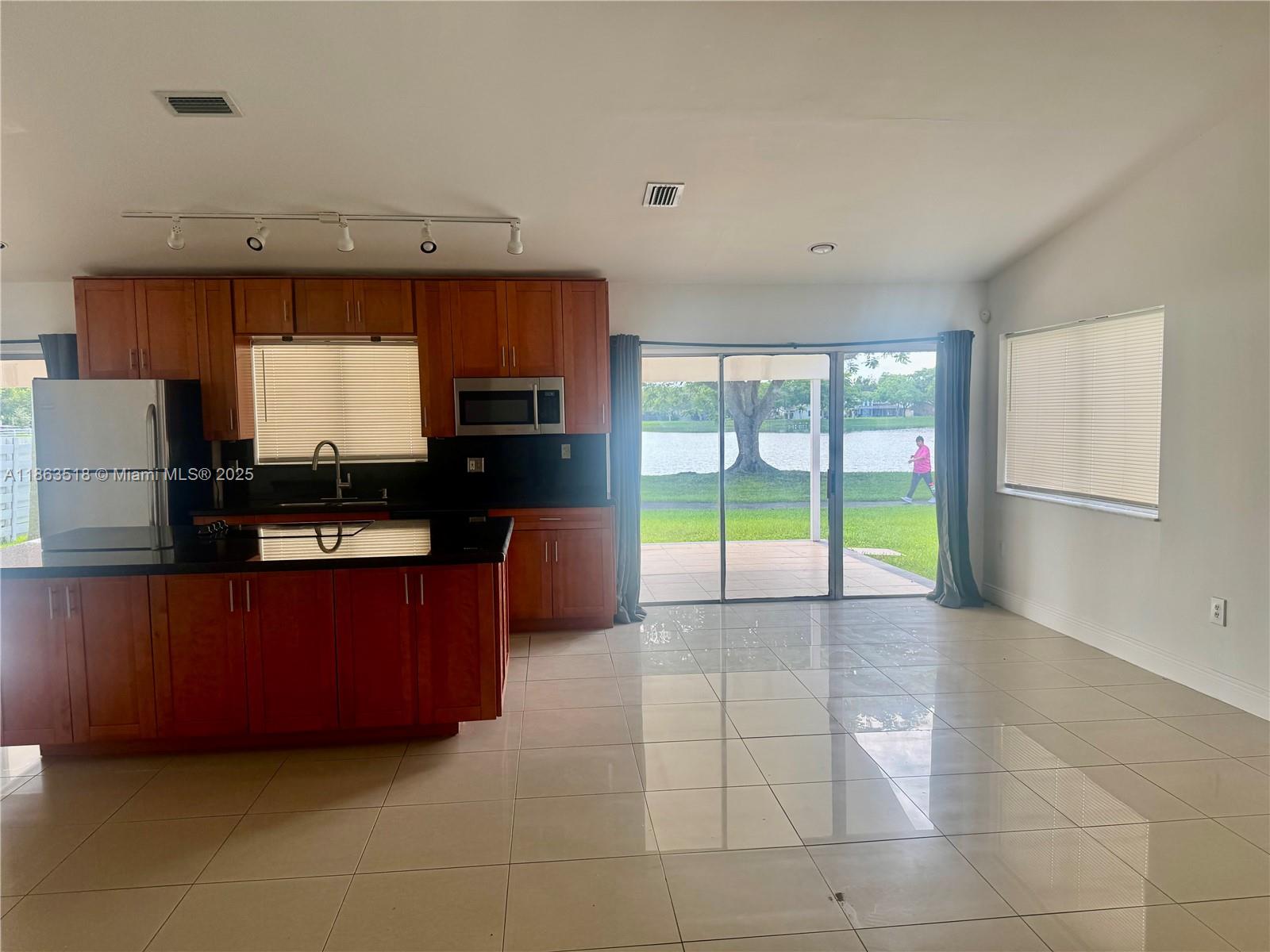 14570 Southwest 145th Place, Unit 14570 Miami, FL 33186 - Photo 11 of 23 a kitchen with granite countertop a refrigerator and a stove top oven
