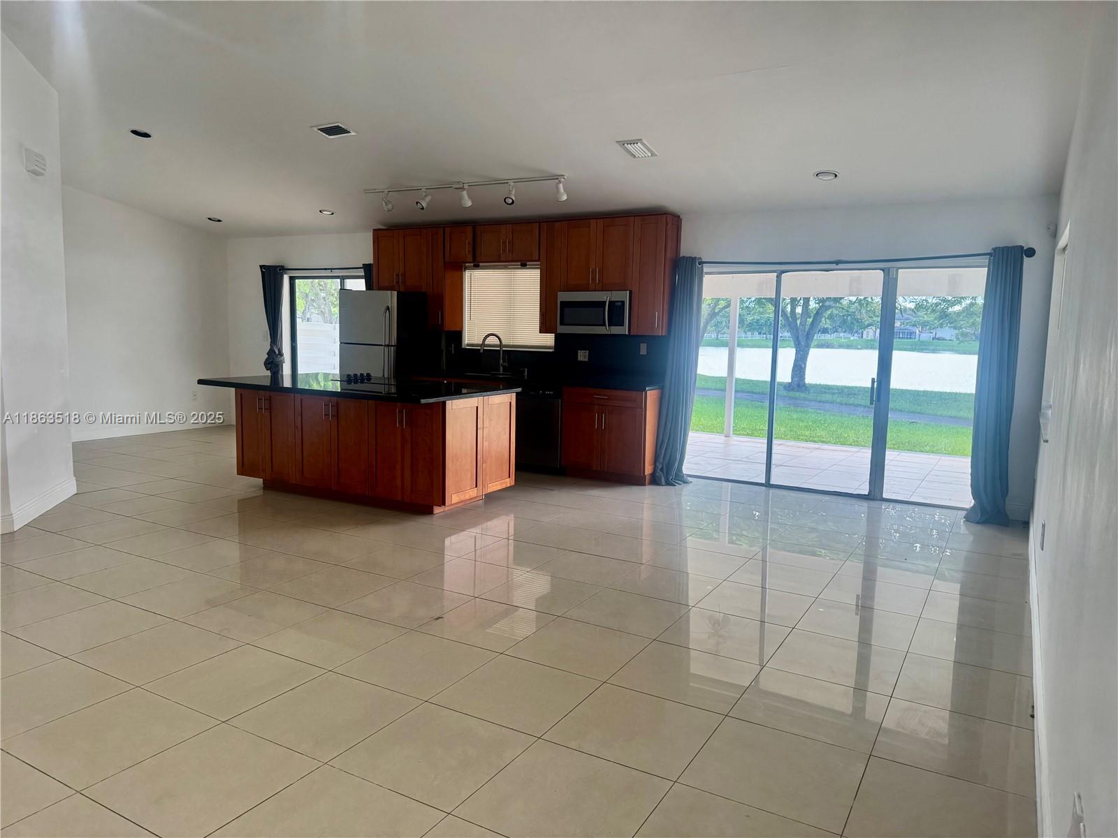 14570 Southwest 145th Place, Unit 14570 Miami, FL 33186 - Photo 12 of 23 a large kitchen with stainless steel appliances a large counter top and a view of living room