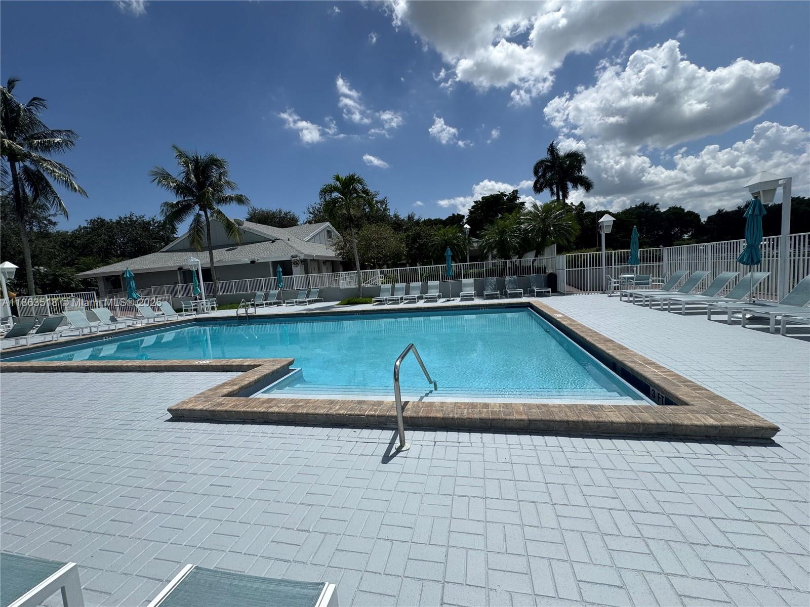 14570 Southwest 145th Place, Unit 14570 Miami, FL 33186 - Photo 21 of 23 a view of a swimming pool with a table and chairs