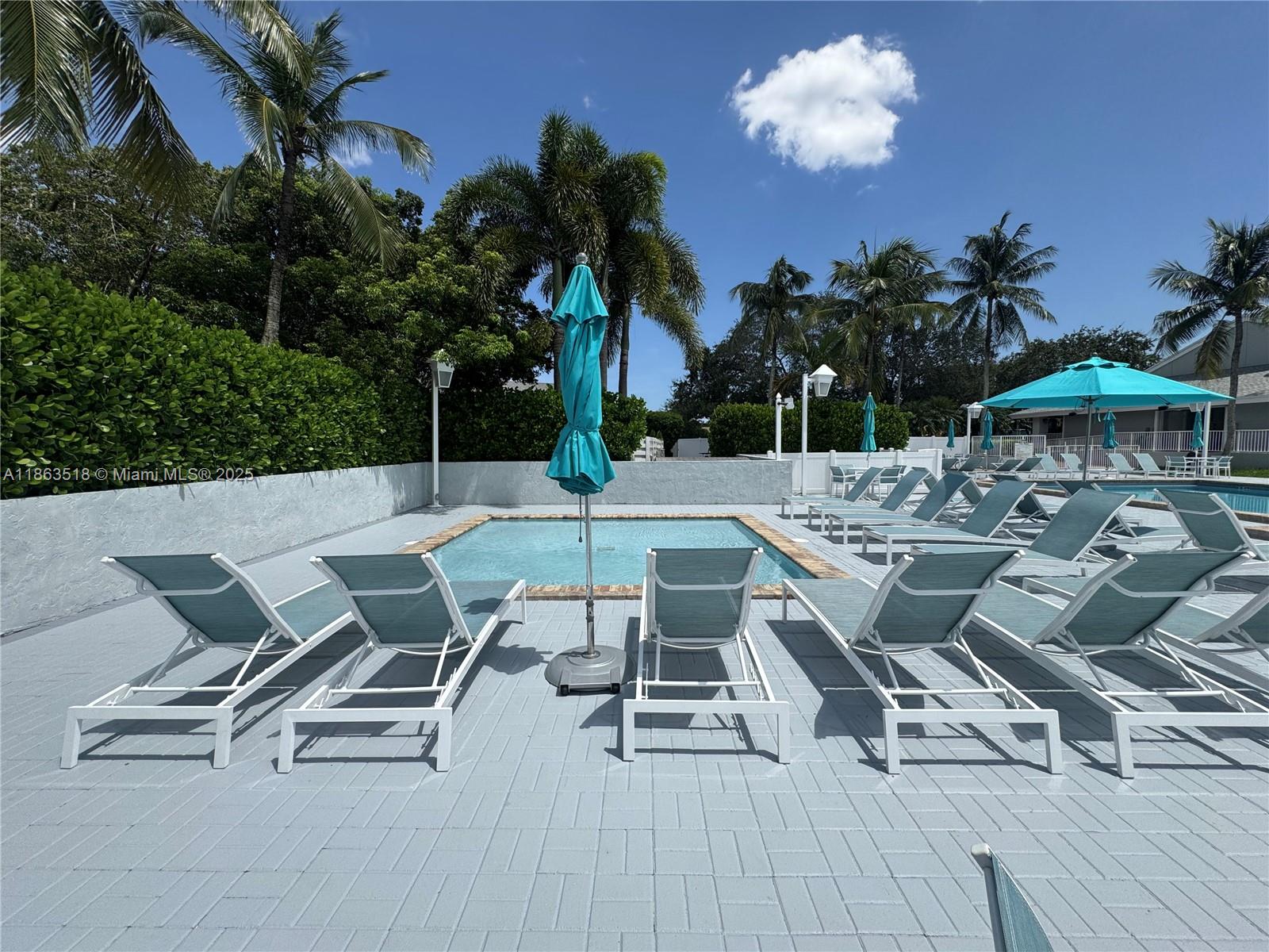 14570 Southwest 145th Place, Unit 14570 Miami, FL 33186 - Photo 22 of 23 a view of a patio with table and chairs potted plants with wooden floor and palm trees
