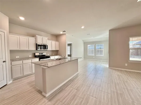 a kitchen with stainless steel appliances granite countertop a stove top oven a sink dishwasher and a refrigerator with wooden floor