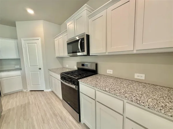 a kitchen with stainless steel appliances granite countertop a stove a sink and a microwave