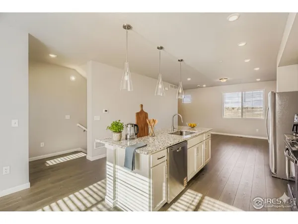 a kitchen with stainless steel appliances granite countertop a sink a stove a refrigerator and a wooden floor