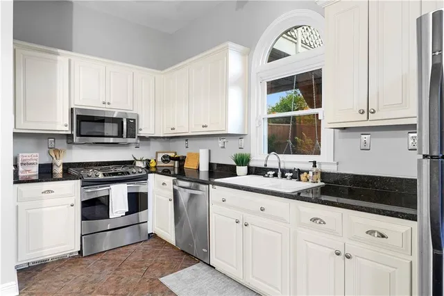 a kitchen with granite countertop white cabinets and stainless steel appliances