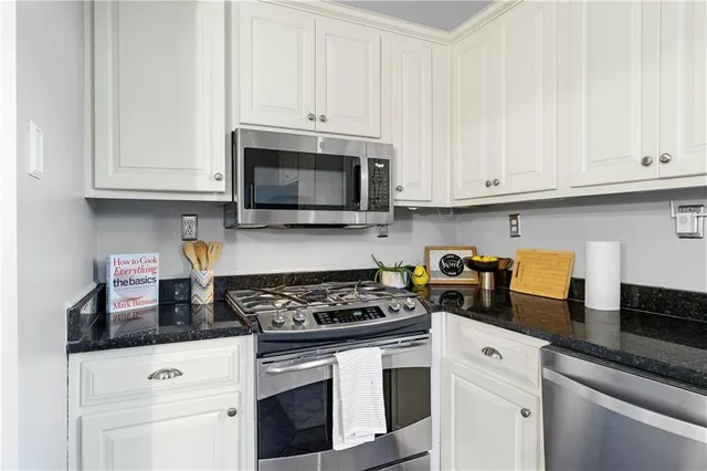 a kitchen with granite countertop white cabinets and stainless steel appliances