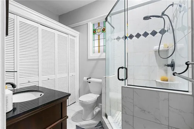 a bathroom with a granite countertop sink a toilet and shower