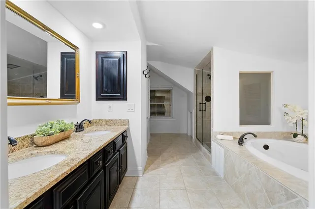 a bathroom with a tub double vanity sink and mirror