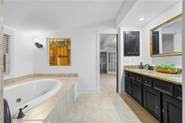 a spacious bathroom with a tub sink and mirror