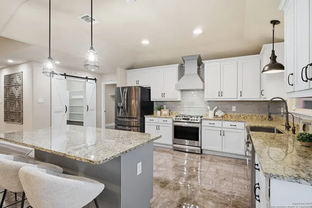 a large kitchen with kitchen island a large counter top space appliances and cabinets