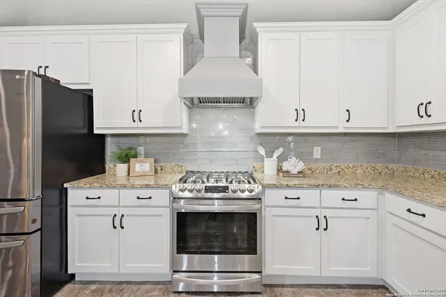 a kitchen with granite countertop white cabinets and stainless steel appliances