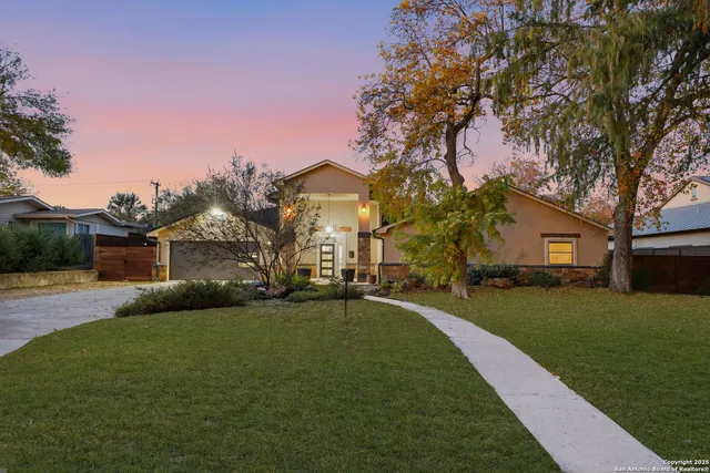 a front view of a house with a garden and tree