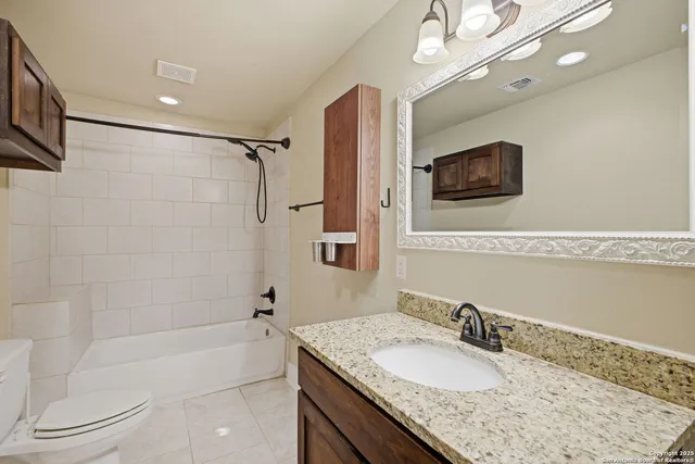 a bathroom with a granite countertop sink a mirror a bathtub and a shower