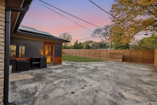 a view of backyard with wooden fence and large trees