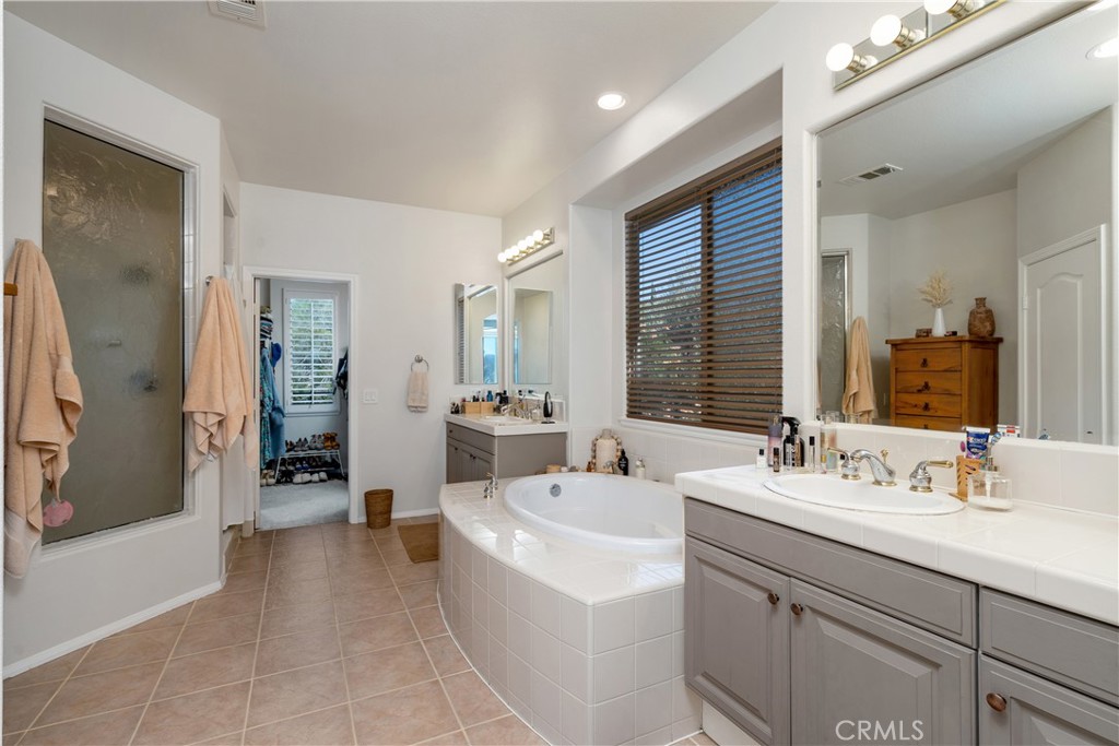 25730 Hawthorne Place Stevenson Ranch, CA 91381 - Photo 25 of 41 a en suite bathroom with a double vanity sink a mirror and a bathtub