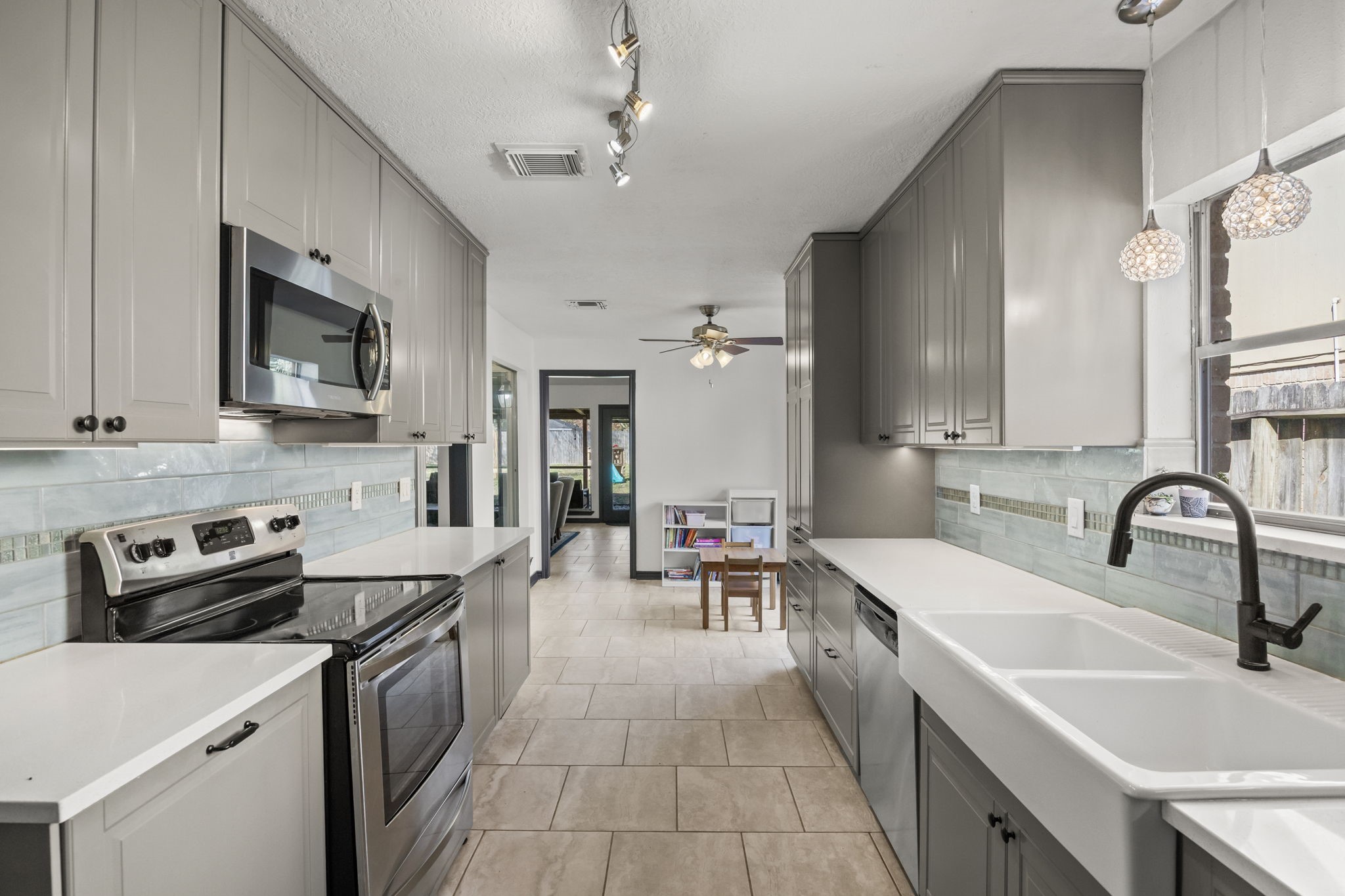 810 Hidden Canyon Road Katy, TX 77450 - Photo 12 of 33 A closer look highlights the modern appliance package, including stainless steel oven and microwave, paired with sleek gray cabinetry and black hardware. Under-cabinet lighting and the textured backsplash add both function and visual interest to this refined kitchen space.