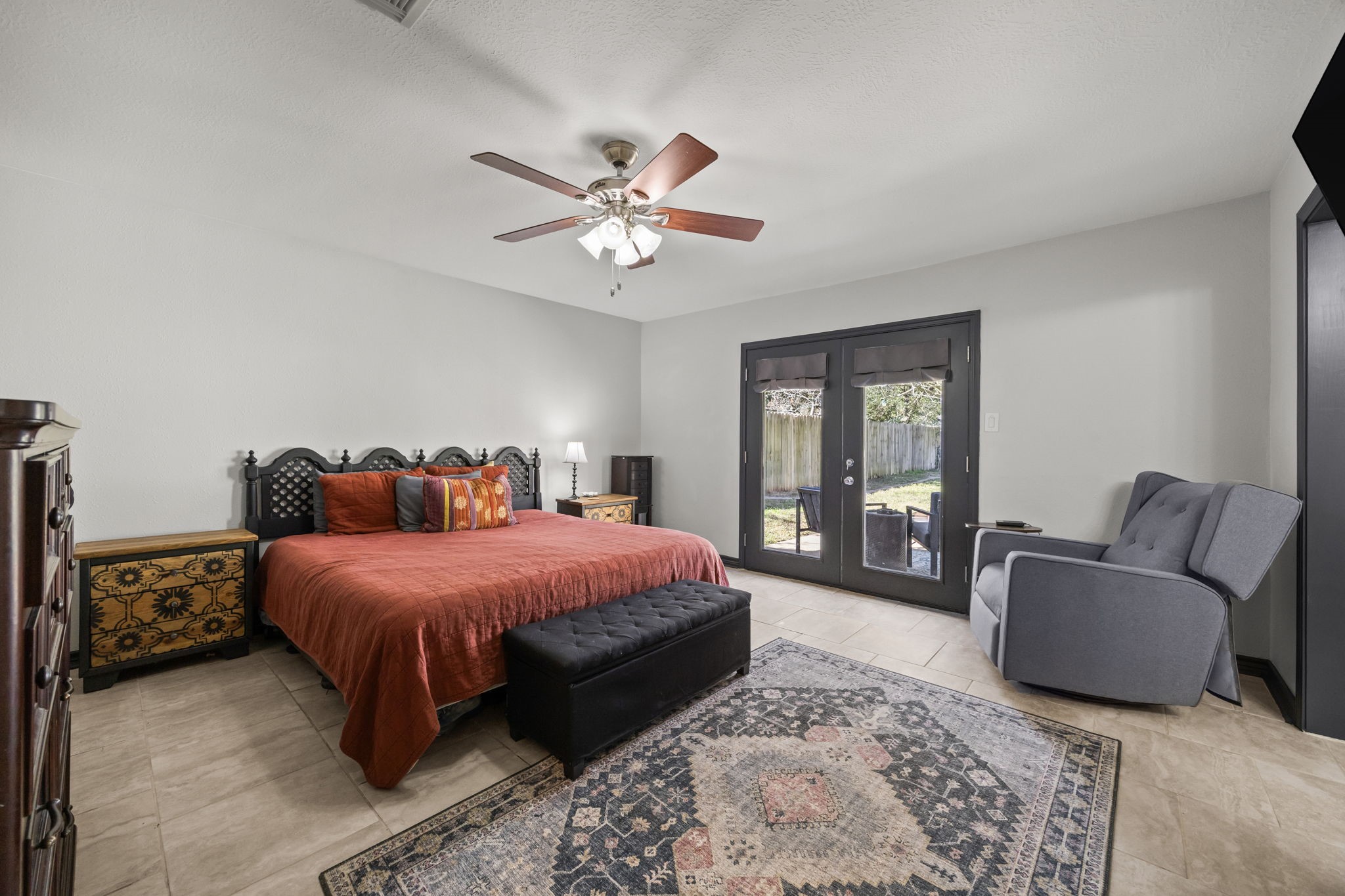 810 Hidden Canyon Road Katy, TX 77450 - Photo 20 of 33 The spacious primary bedroom offers a relaxing retreat with tile flooring, soft neutral walls, and a ceiling fan with light for year-round comfort. Generous room dimensions allow for a calm and functional space. Double French doors open directly to the backyard, filling the bedroom with natural light.