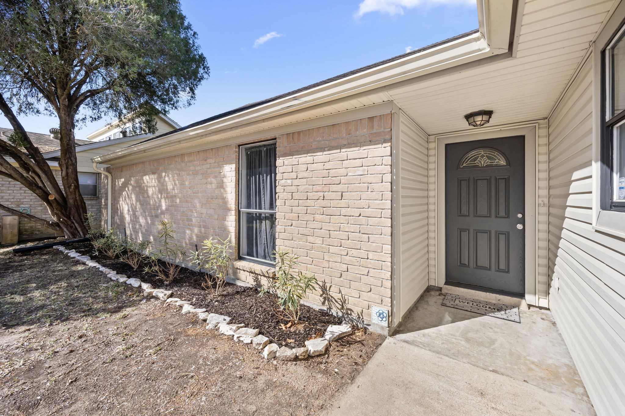 810 Hidden Canyon Road Katy, TX 77450 - Photo 2 of 33 A closer view of the inviting front entry highlights the home’s classic brick exterior paired with clean siding accents. Landscaping frames the walkway, while the bold front door with decorative glass inset adds curb appeal and a welcoming first impression.