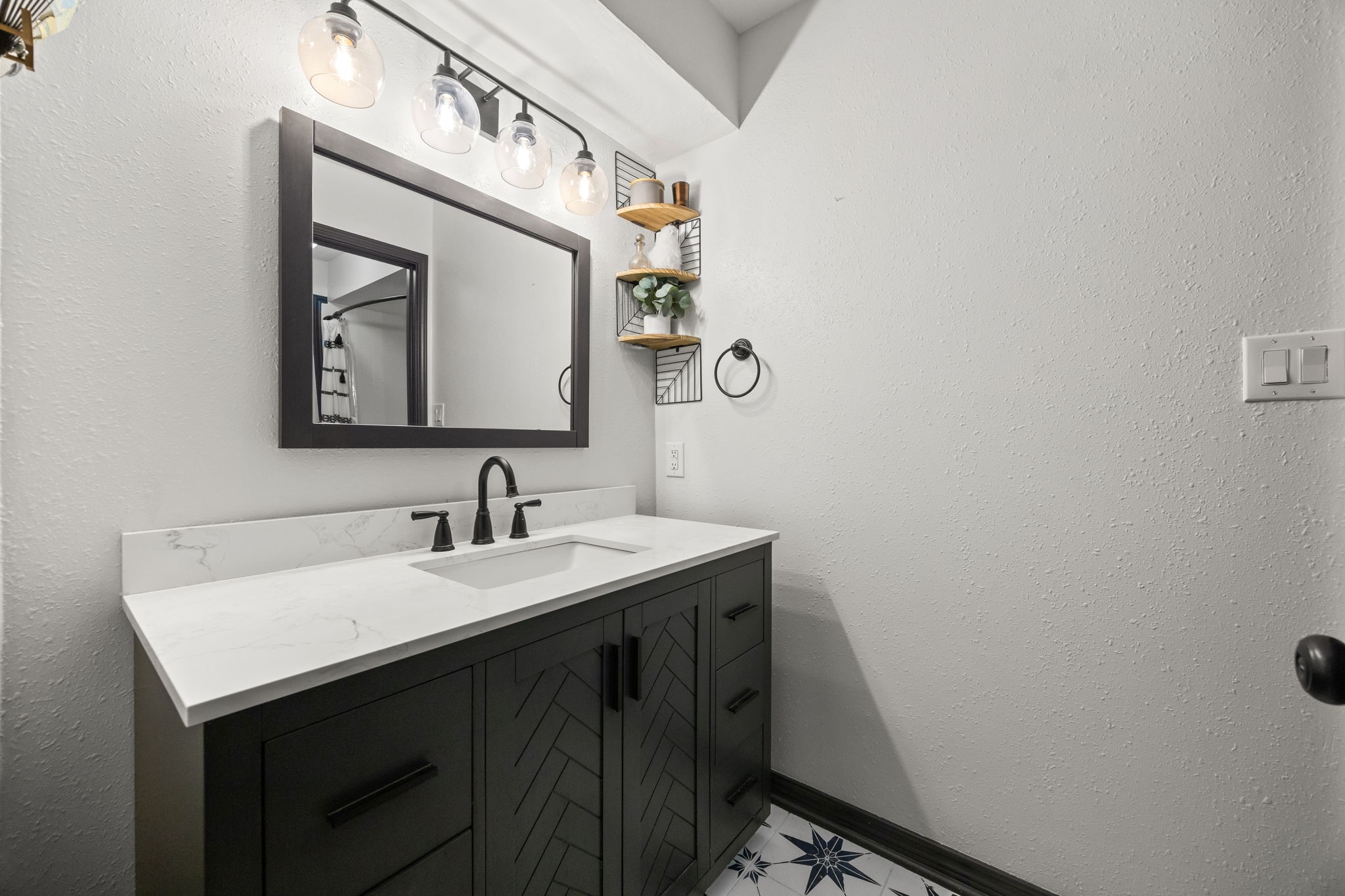 810 Hidden Canyon Road Katy, TX 77450 - Photo 26 of 33 The updated secondary bathroom showcases a stylish vanity with quartz countertop, undermount sink, and modern black fixtures. Accent shelving and contemporary lighting add both function and visual appeal.