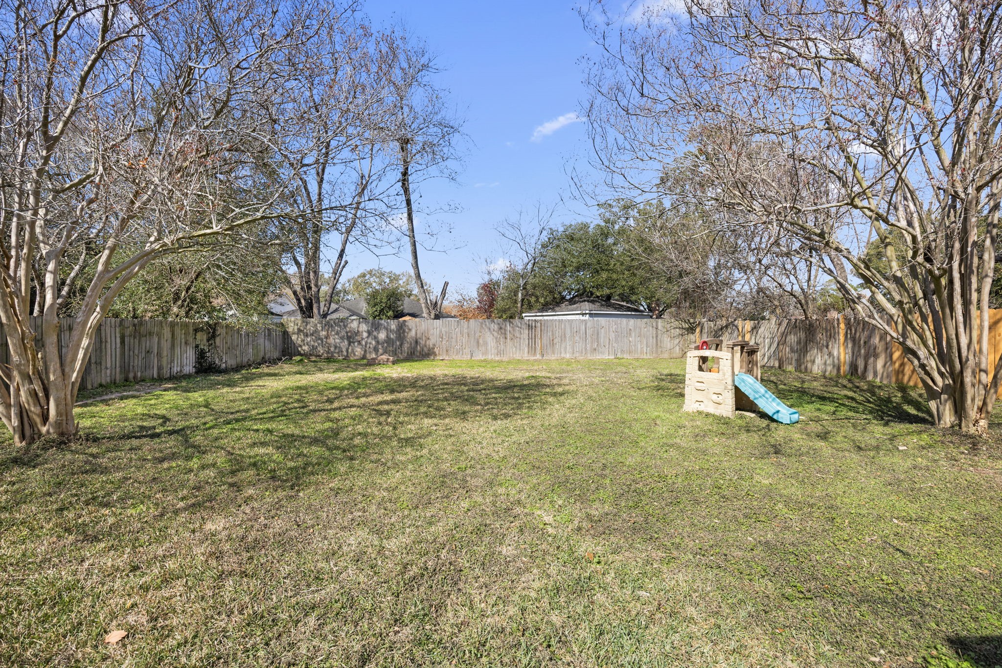 810 Hidden Canyon Road Katy, TX 77450 - Photo 31 of 33 A wide view of the backyard highlights the generous grassy lawn, offering ample space for play, pets, gardening, or future outdoor enhancements. Mature trees provide natural shade and privacy throughout the yard.