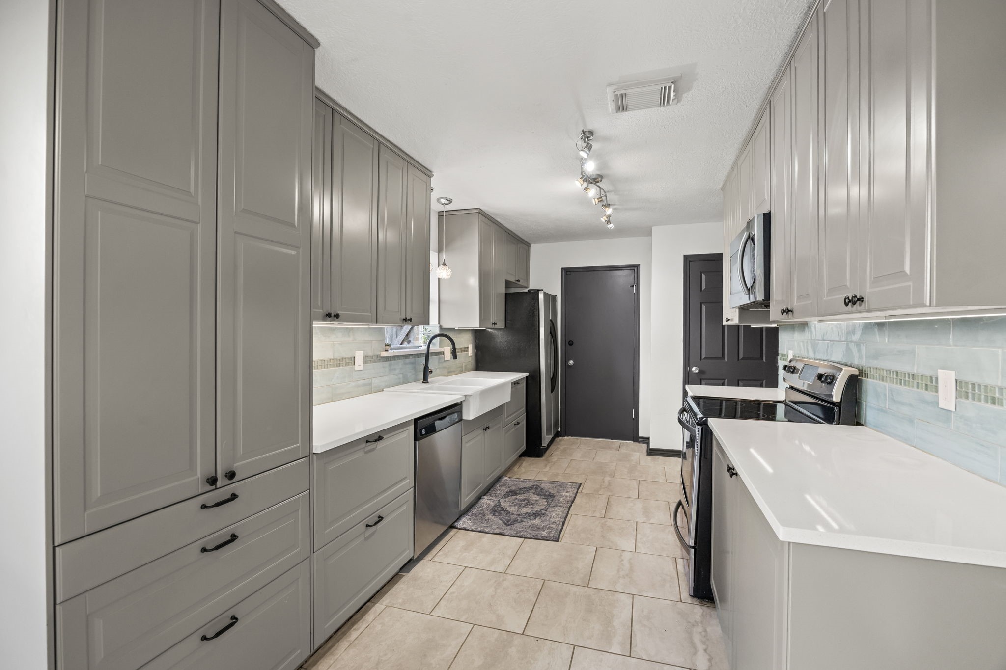 810 Hidden Canyon Road Katy, TX 77450 - Photo 10 of 33 This beautifully updated galley kitchen features an efficient layout with abundant cabinetry on both sides, quartz countertops, and tile flooring for durability and easy maintenance. Track lighting and under-cabinet illumination brighten the workspace, making meal prep effortless.