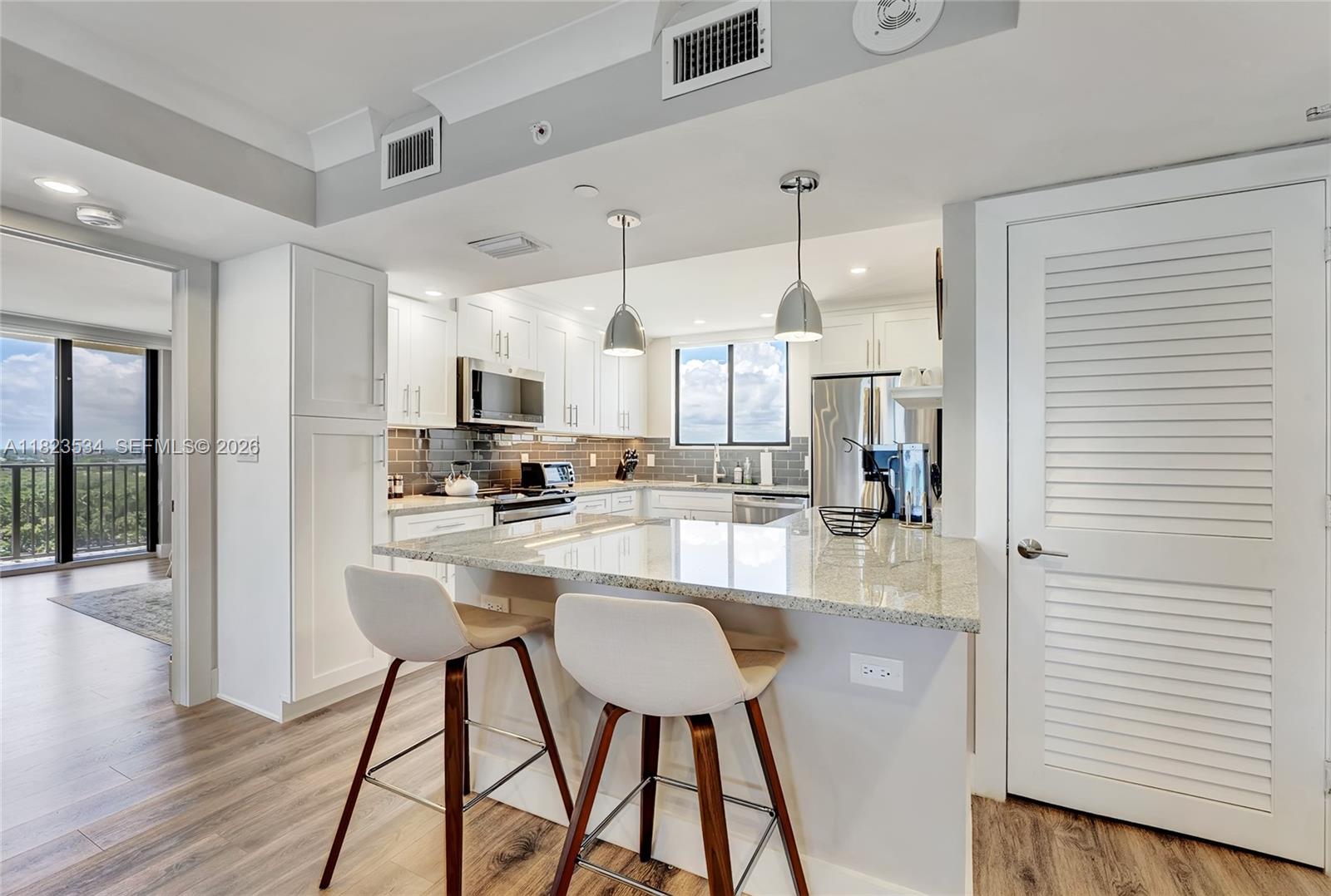 200 Ocean Trail Way, Unit 701 Jupiter, FL 33477 - Photo 11 of 40 a kitchen with stainless steel appliances kitchen island granite countertop a refrigerator a stove and white cabinets with wooden floor
