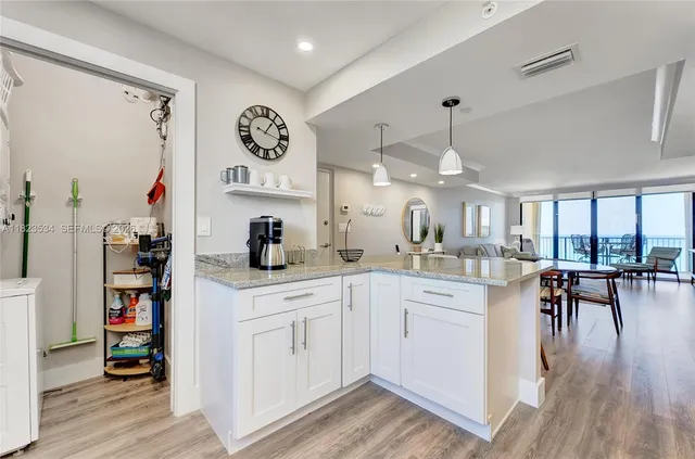 a kitchen with white cabinets and wooden floor