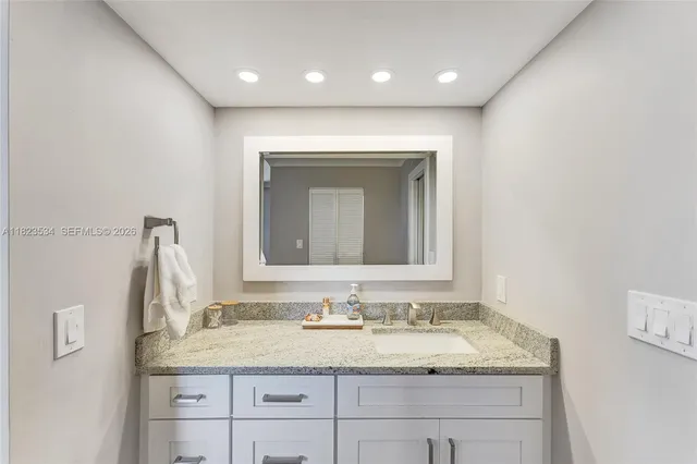 a bathroom with a granite countertop sink and a mirror