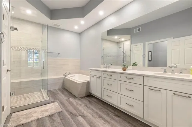 a spacious bathroom with a double vanity sink a large mirror and shower