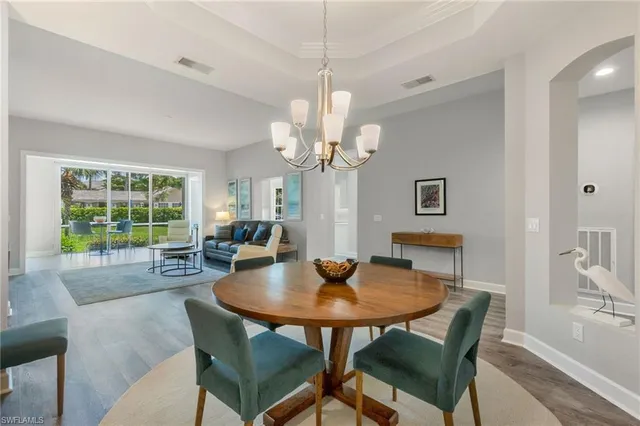 a dining room with wooden floor a chandelier a wooden table and chairs
