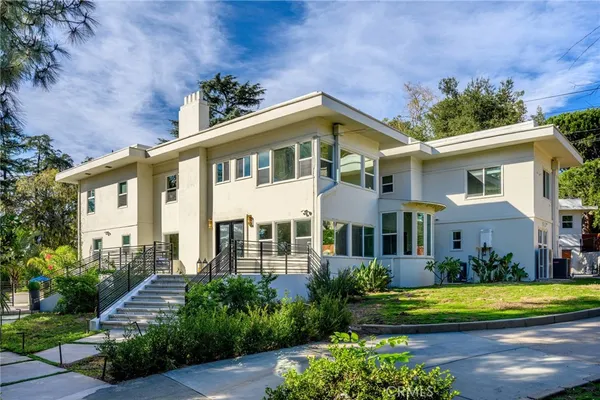 a front view of a house with a garden and trees