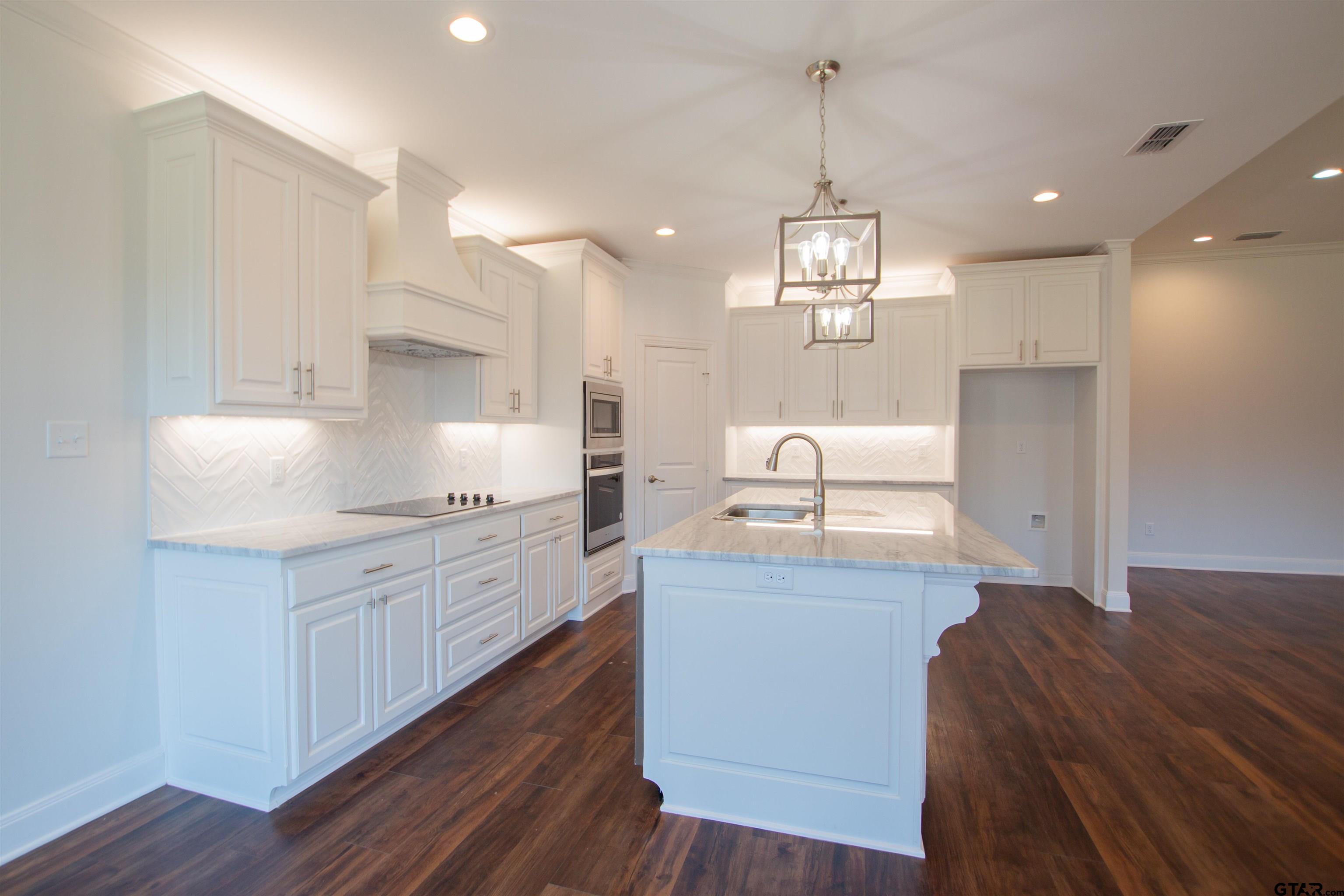 14716 Fallow Lane Tyler, TX 75706 - Photo 8 of 46 a open kitchen with kitchen island white cabinets appliances and a chandelier