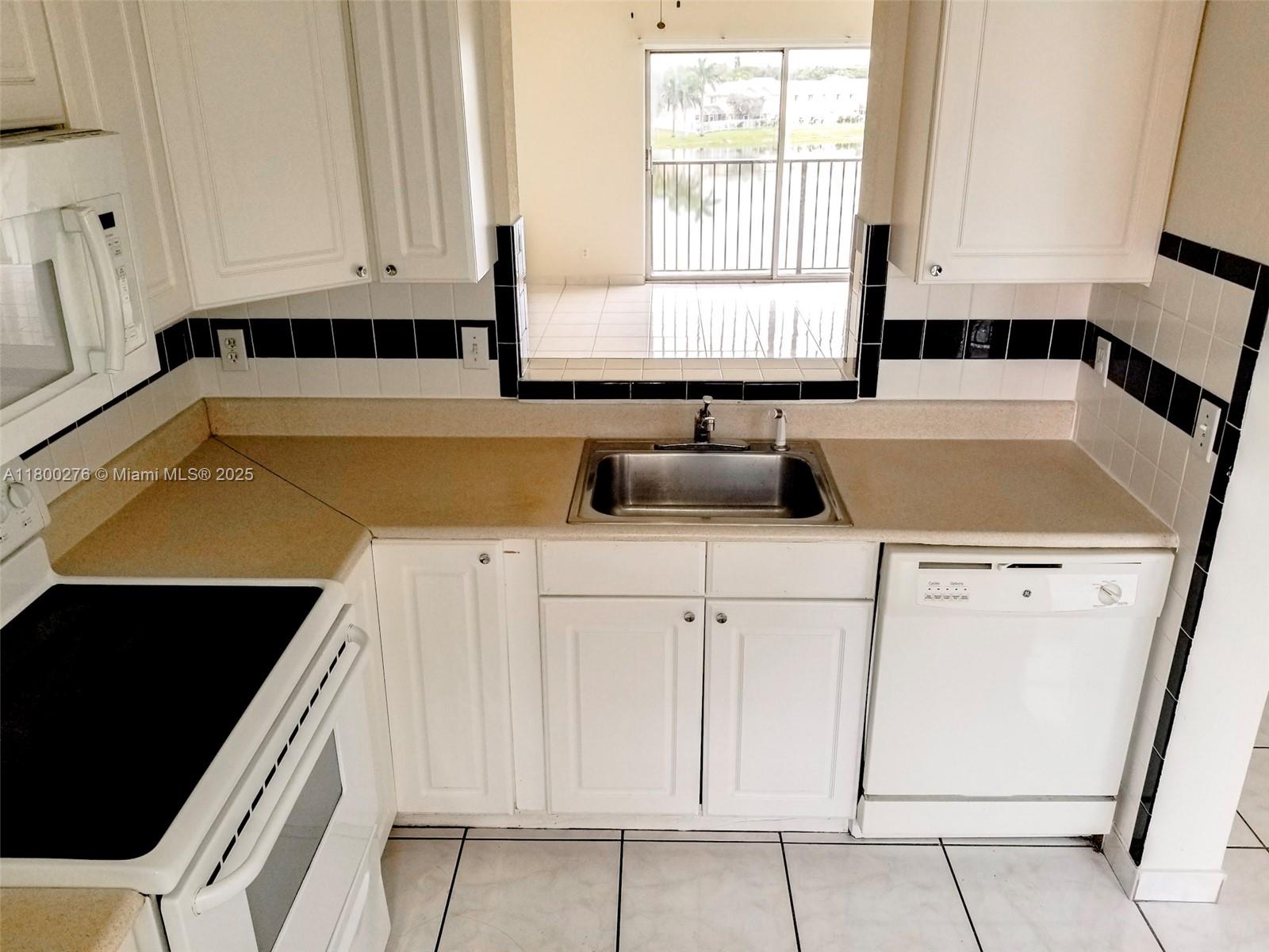 8560 Sherman Circle North, Unit 402 Miramar, FL 33025 - Photo 2 of 19 a kitchen with white cabinets and window