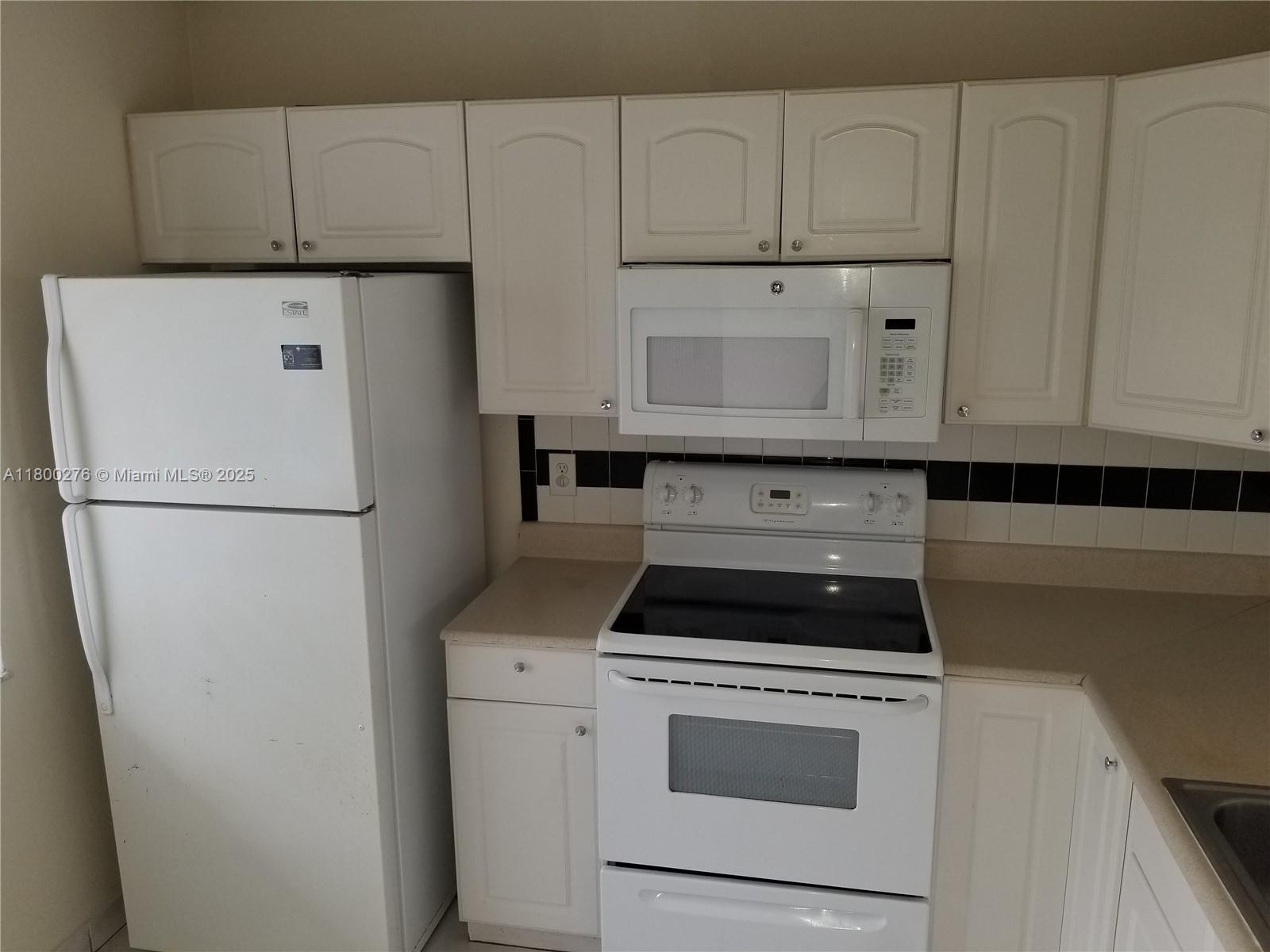 8560 Sherman Circle North, Unit 402 Miramar, FL 33025 - Photo 3 of 19 a kitchen with appliances a refrigerator and cabinets